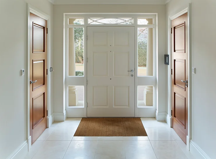 White door at entrance to house flanked on both sides by 2 brown doors 