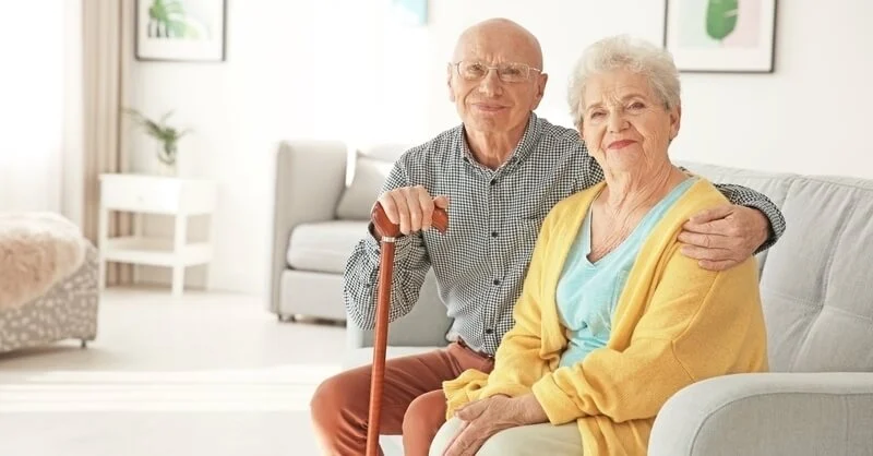 Reasons Why Seniors Leave Their Homes elderly husband and wife sitting on home couch – TC Habitat
