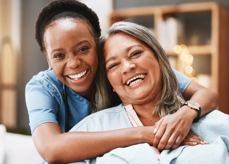 Young aide hugging elderly patient