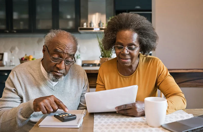 Senior woman and man sitting at the table at home and going through bills v2