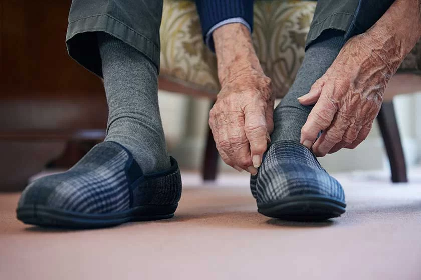 close senior man putting slippers keep feet warm cost living